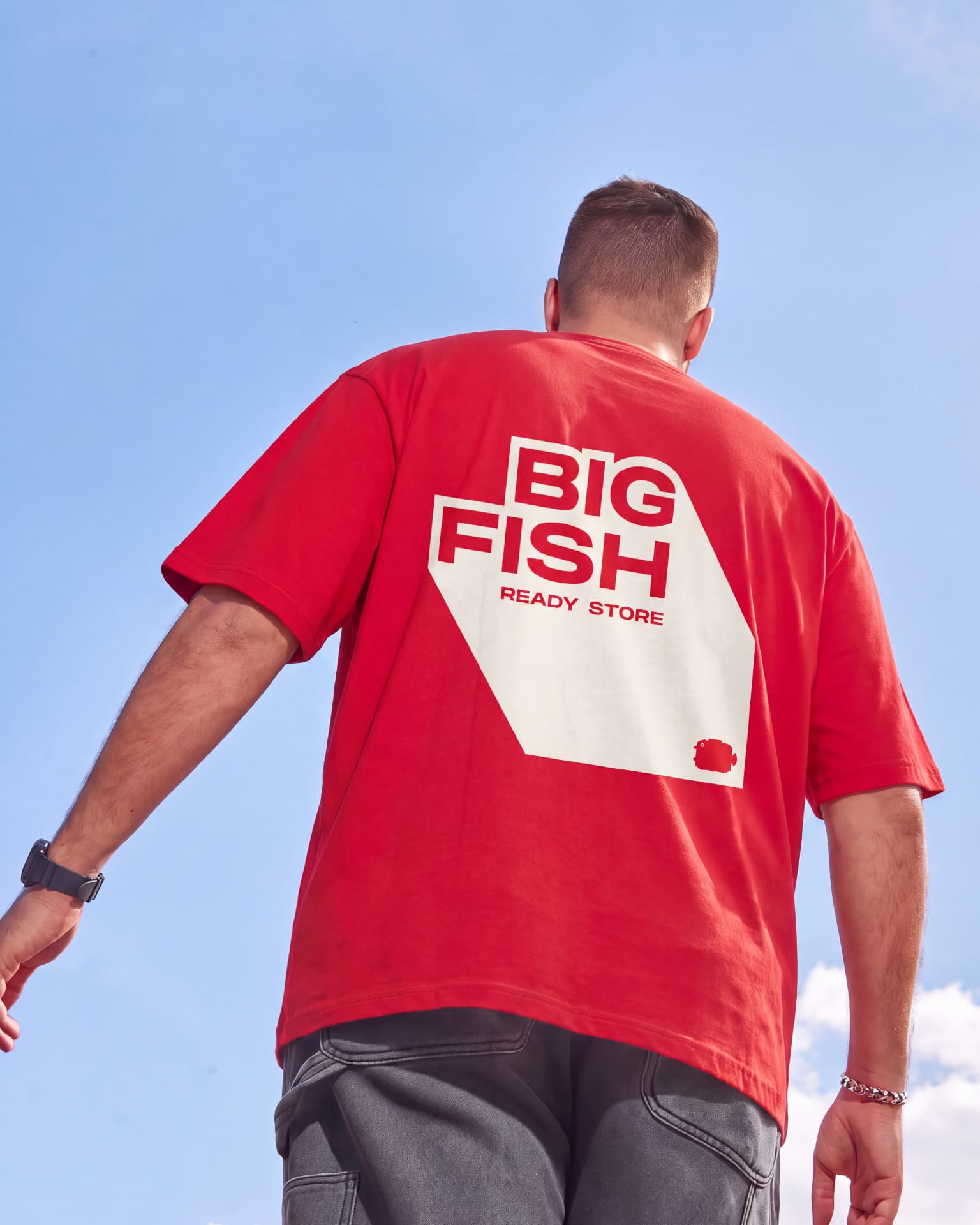 Persona con la camiseta roja de BIG FISH Ready Store bajo el cielo azul